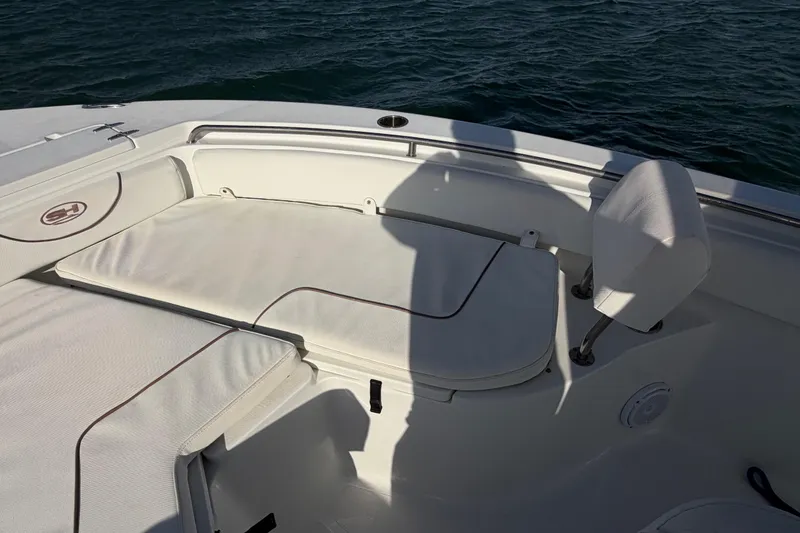 Slide: The Image of 2018 Sea Hunt Ultra 235 SE boat interior with cushioned seating and ocean backdrop. - 22