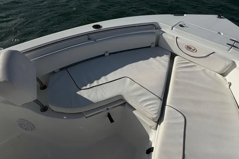 Slide: The Image of 2018 Sea Hunt Ultra 235 SE boat interior with cushioned seating and ocean backdrop. - 25