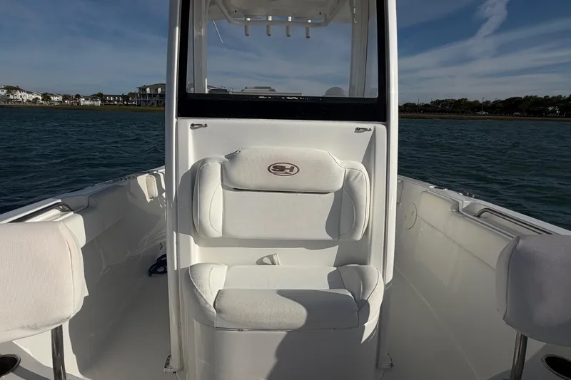 Slide: The Image of 2018 Sea Hunt Ultra 235 SE boat interior with cushioned seating on calm water. - 28