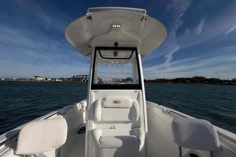 Slide: The Image of 2018 Sea Hunt Ultra 235 SE boat on water, showcasing helm and seating under clear sky. - 29