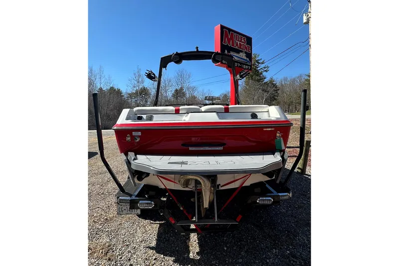 Slide: The Image of 2024 Axis A20 boat, red and white, parked outdoors with clear blue sky. - 2