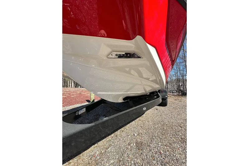 Slide: The Image of Red and white 2024 Axis A20 boat hull on a trailer, parked outdoors. - 22
