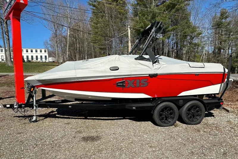 Slide: The Image of 2024 Axis A20 boat in red, covered, on a trailer in a wooded area. - 26