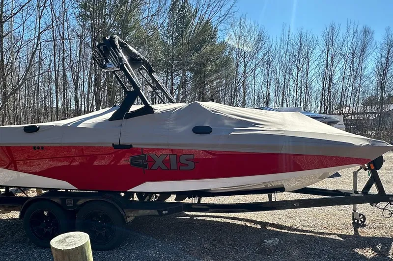 Slide: The Image of 2024 Axis A20 boat covered on trailer, parked outdoors in wooded area. - 28