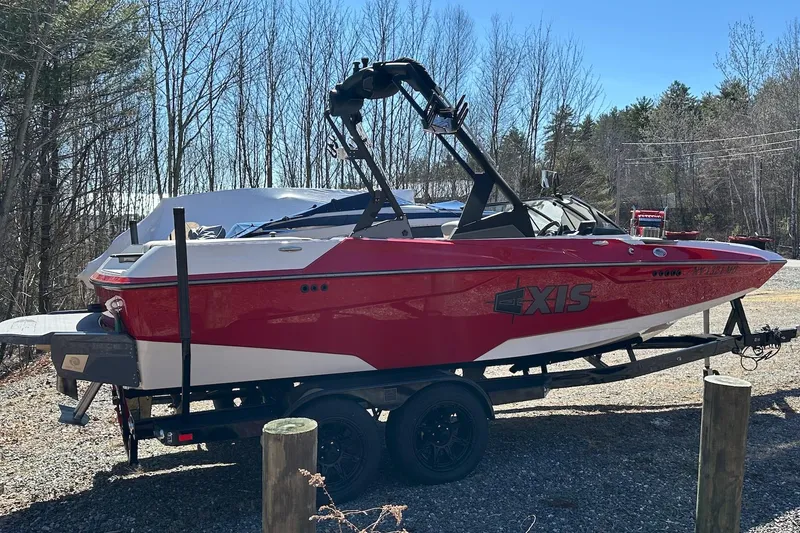 Slide: The Image of 2024 Axis A20 boat in red on a trailer, parked outdoors near trees. - 3