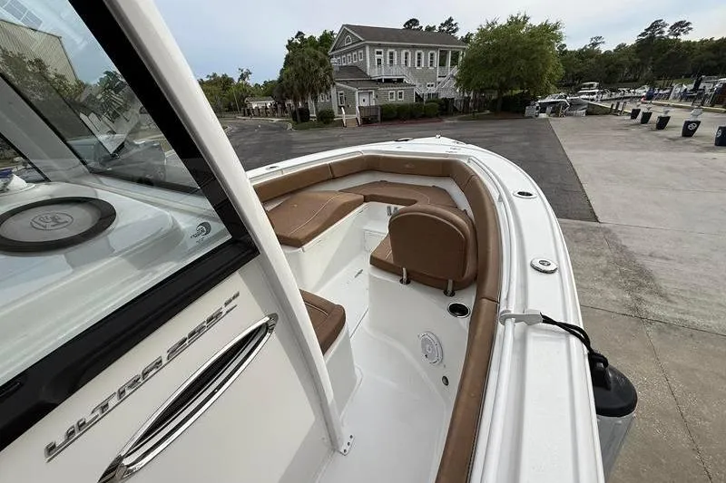 Slide: The Image of 2023 Sea Hunt Ultra 255 SE boat with brown seating, docked near a marina. - 29