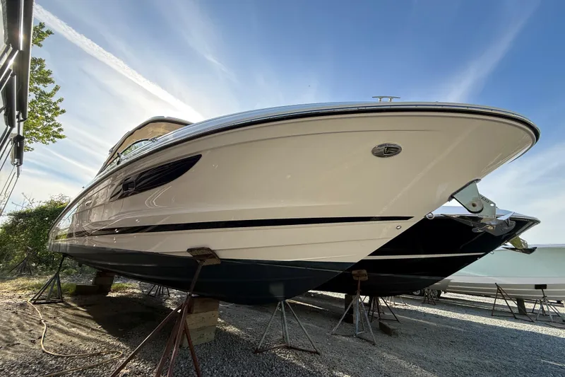 Slide: The Image of 2014 Sea Ray SLX 350 boat with American flag, parked beside an RV under clear blue sky. - 2