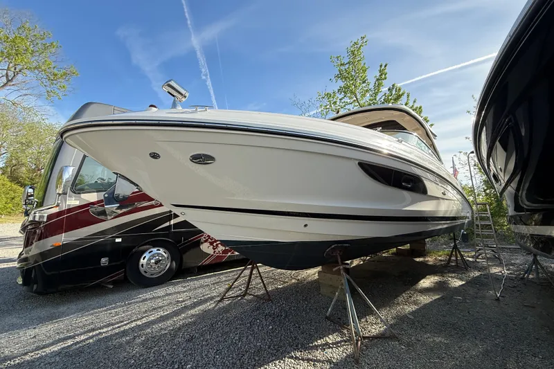Slide: The Image of 2014 Sea Ray SLX 350 boat on stands, parked beside an RV, under a clear sky. - 25