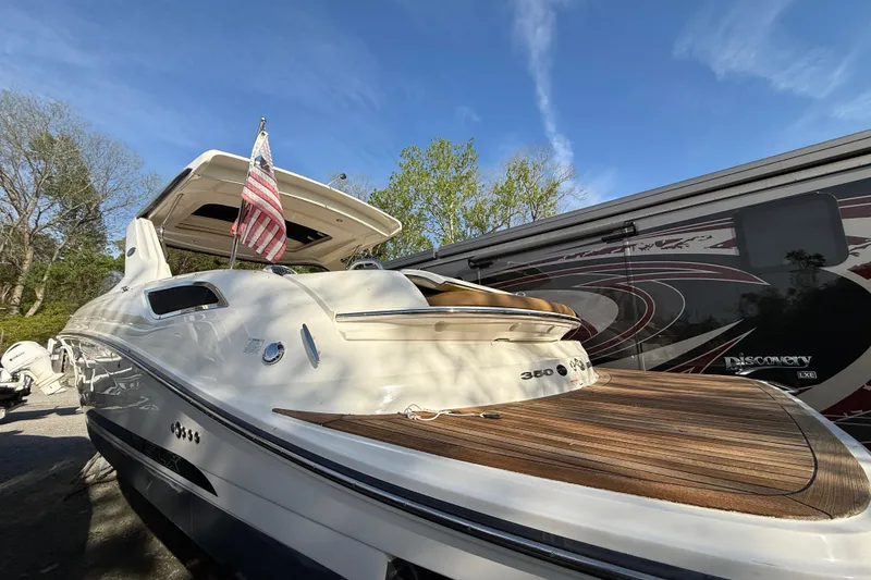 Slide: The Image of 2014 Sea Ray SLX 350 boat with American flag, parked beside an RV under clear blue sky. - 26