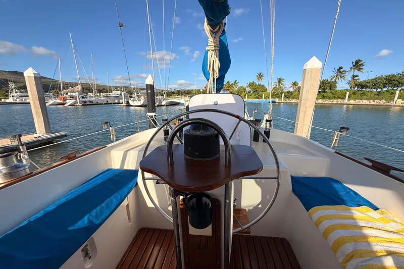 Slide: The Image of 1978 Morgan 452 sailboat cockpit with marina view, featuring blue cushions and a wooden steering wheel. - 2
