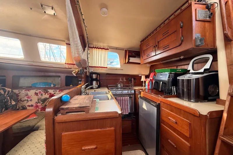 Slide: The Image of 1978 Morgan 452 yacht interior with wooden cabinetry, kitchen appliances, and floral seating. - 26