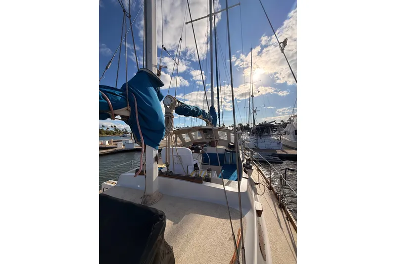Slide: The Image of 1978 Morgan 452 sailboat docked under a sunny sky with blue sails. - 30