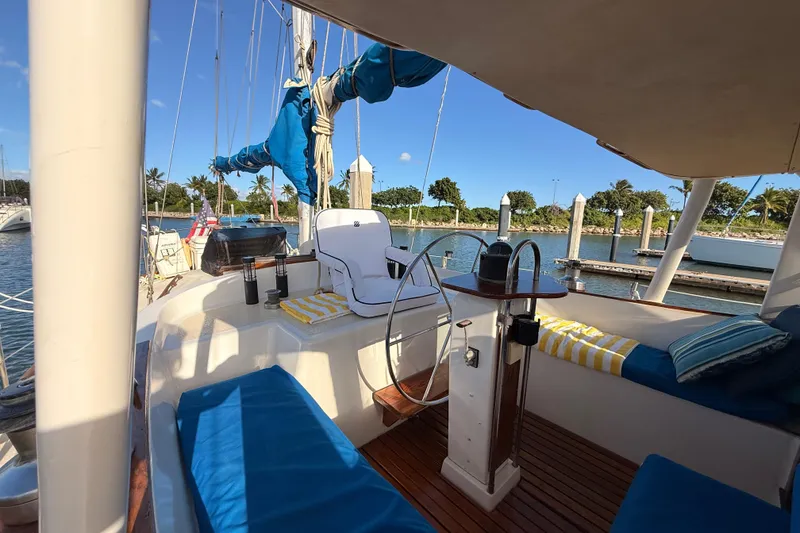Slide: The Image of 1978 Morgan 452 sailboat cockpit with blue cushions, docked in a sunny marina. - 33