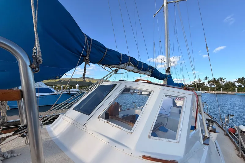 Slide: The Image of 1978 Morgan 452 sailboat docked, featuring blue sails and a clear sky backdrop. - 42