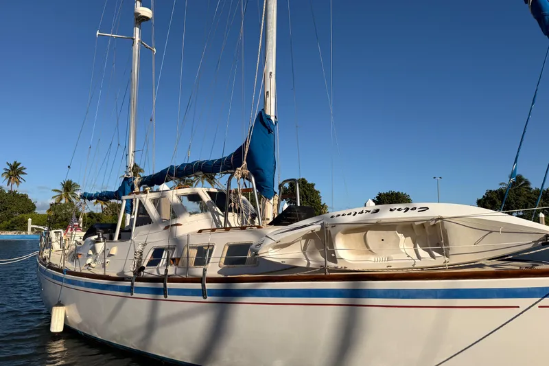 Slide: The Image of 1978 Morgan 452 sailboat docked under clear blue sky, surrounded by palm trees. - 62