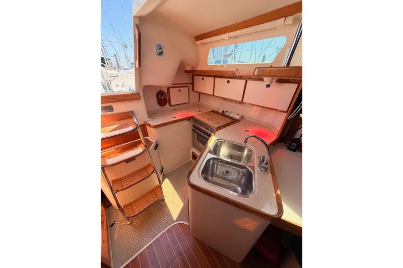 Slide: The Image of Interior of 1999 Catalina 320 sailboat kitchen with sink, stove, and wooden cabinetry. - 25
