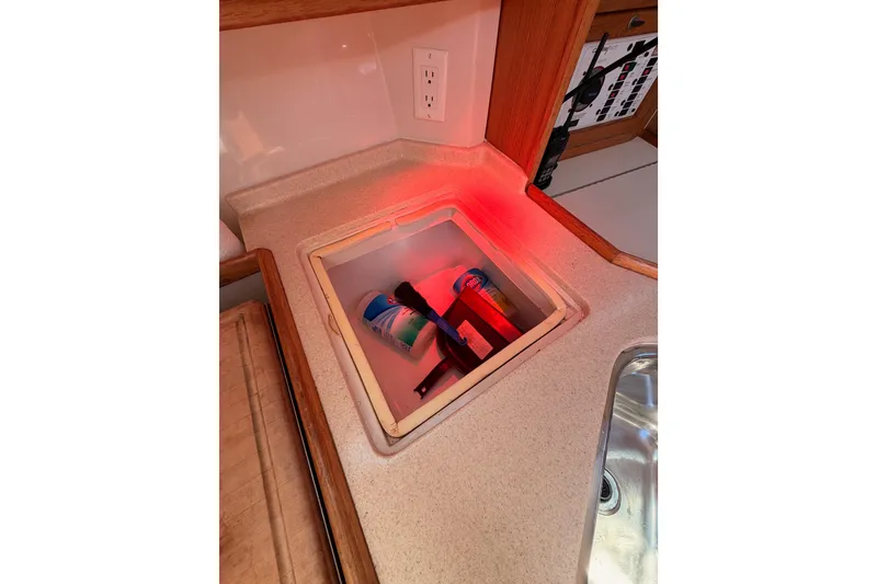 Slide: The Image of Storage compartment in a 1999 Catalina 320 sailboat galley, featuring cleaning supplies. - 29