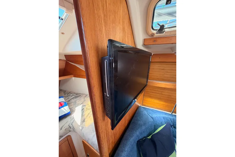 Slide: The Image of Interior of a 1999 Catalina 320 sailboat with mounted TV and cozy cabin space. - 45