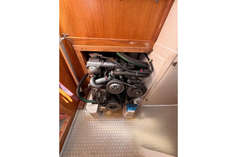 Slide: The Image of Engine compartment of a 1999 Catalina 320 sailboat, showcasing mechanical components and wooden paneling. - 52