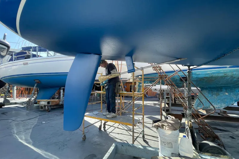 Slide: The Image of Person working on a 1999 Catalina 320 sailboat hull in a boatyard. - 60