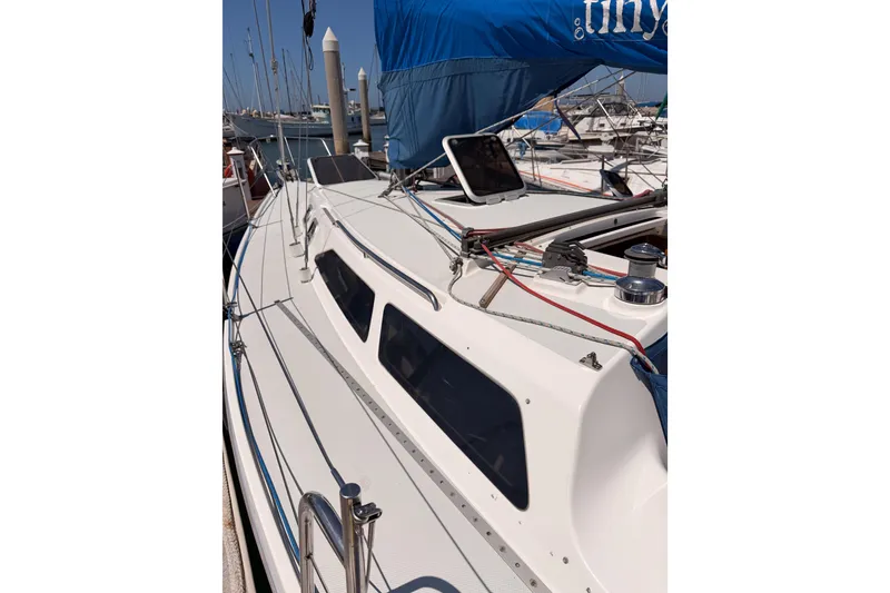 Slide: The Image of 1999 Catalina 320 sailboat docked, featuring sleek deck design and blue sail cover. - 7
