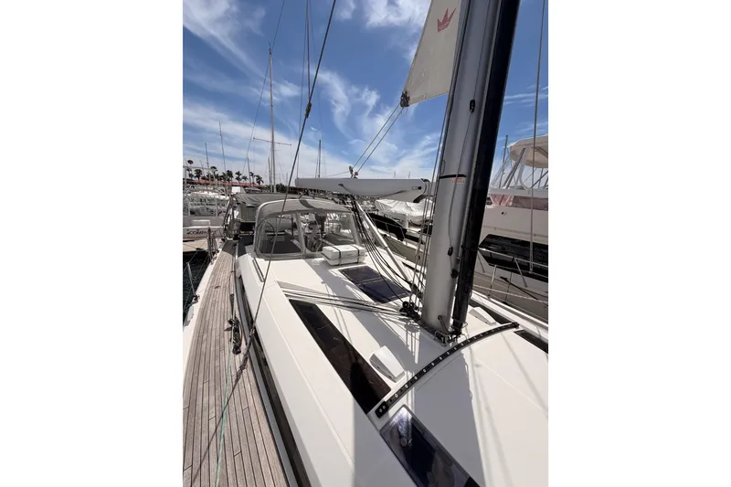 Slide: The Image of 2020 Beneteau Oceanis 51.1 sailboat docked, showcasing sleek deck design and mast under blue sky. - 23