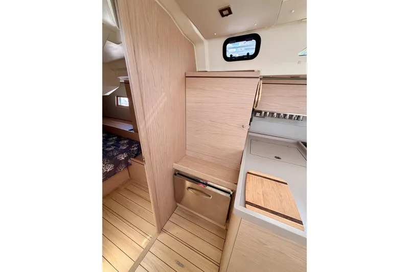 Slide: The Image of Interior of 2020 Beneteau Oceanis 51.1 yacht, featuring modern wood cabinetry and compact kitchen area. - 52