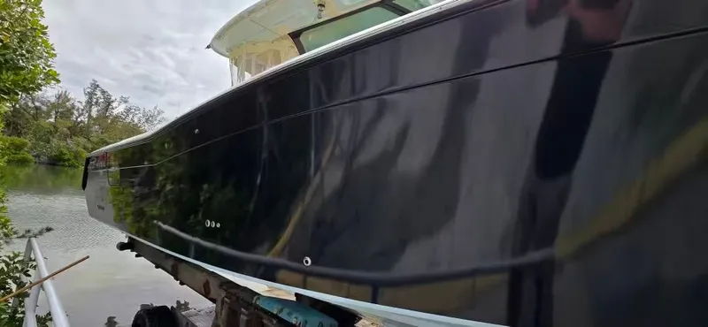 Slide: The Image of 2024 Grady-White Canyon 386 boat by water, glossy black exterior hull. - 5