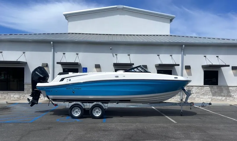 The Image of 2026 Bayliner VR6OB boat on trailer in front of building. - 1