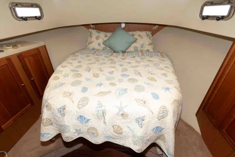 Slide: The Image of Cozy cabin bedroom in 2005 Mainship 400 Trawler with nautical-themed bedding. - 25