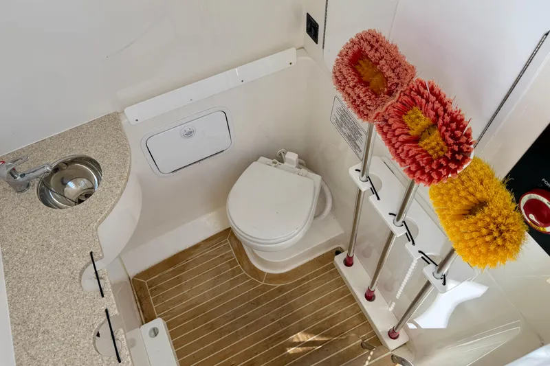 Slide: The Image of 2019 Regulator 31 boat bathroom with sink, toilet, and cleaning brushes. - 44