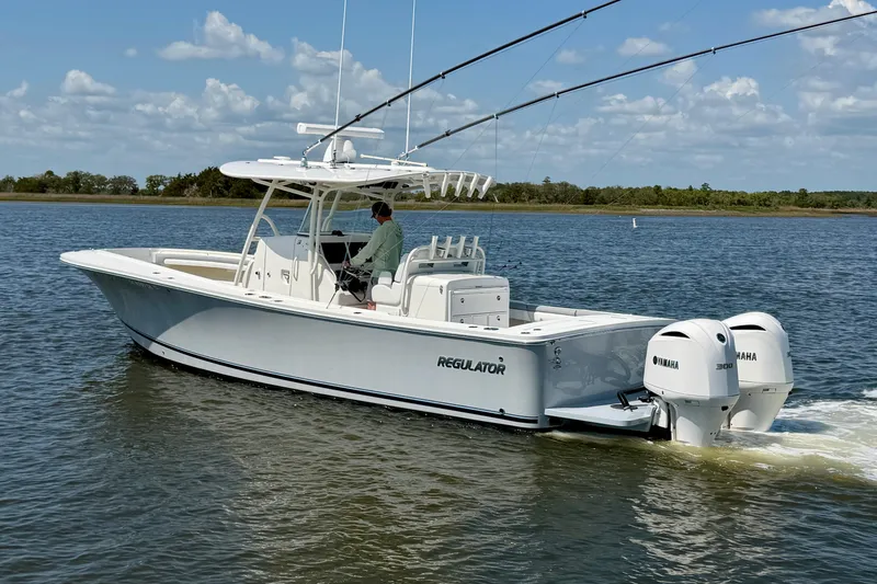 Slide: The Image of 2019 Regulator 31 boat cruising on a calm lake with dual Yamaha engines. - 6