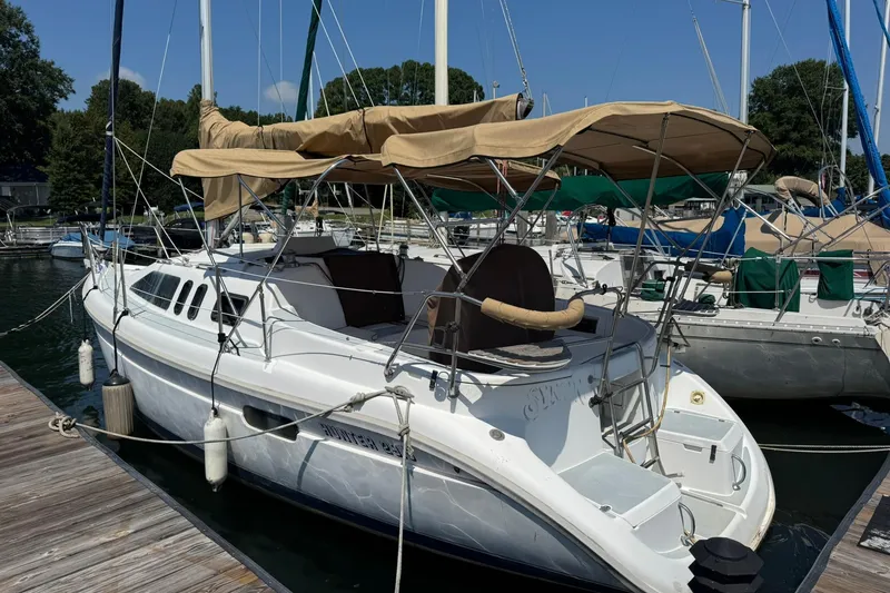 The Image of 1994 Hunter 29.5 sailboat docked at marina with tan canopy and white hull. - 0
