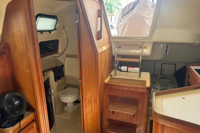 Slide: The Image of Interior of a 1994 Hunter 29.5 sailboat featuring a compact bathroom and wooden cabinetry. - 22