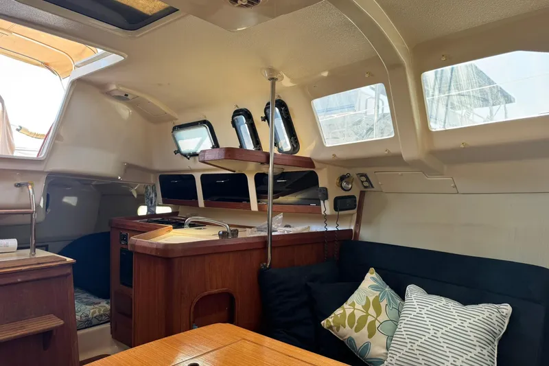 Slide: The Image of Interior of a 1994 Hunter 29.5 sailboat with cozy seating and wooden cabinetry. - 29