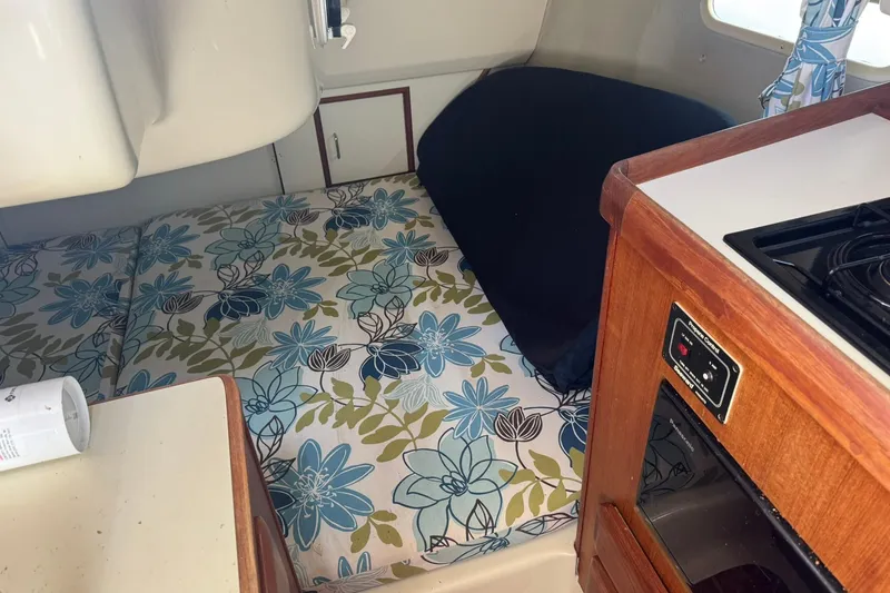 Slide: The Image of Interior of 1994 Hunter 29.5 sailboat with floral cushions and compact kitchen area. - 31