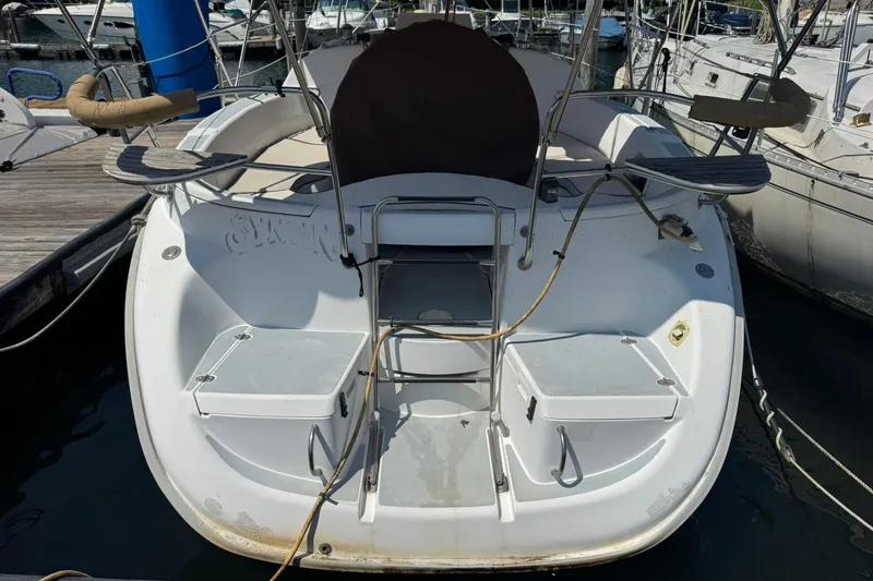 Slide: The Image of 1994 Hunter 29.5 sailboat stern view at marina, showcasing deck and seating area. - 4