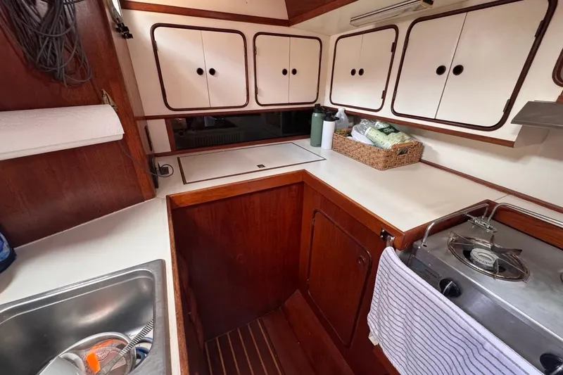 Slide: The Image of 1981 Gulfstar 44 Mk II Center Cockpit Sloop galley with wood cabinetry and compact stove. - 50