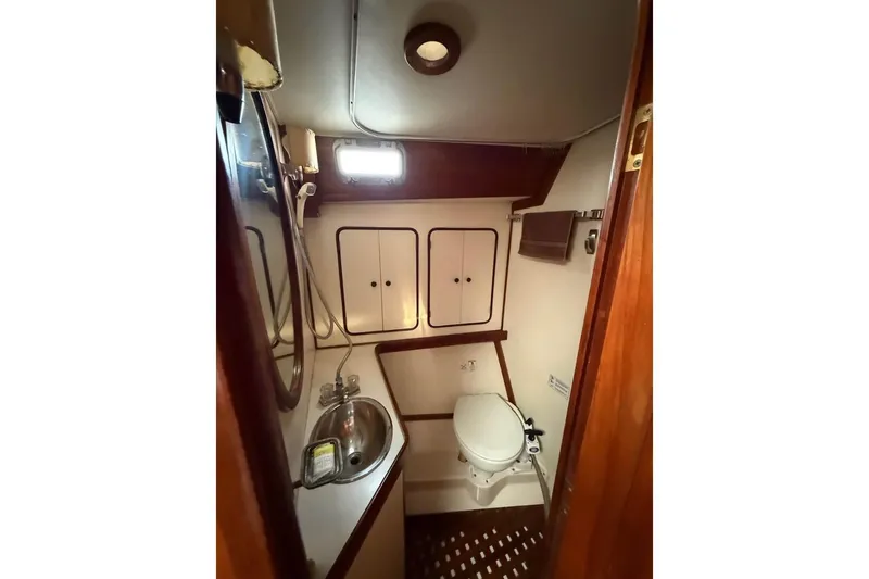 Slide: The Image of 1981 Gulfstar 44 Mk II Center Cockpit Sloop bathroom with sink, toilet, and storage cabinets. - 13