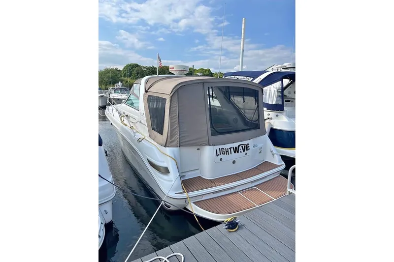 The Image of 1997 Sea Ray Sundancer 330 docked, featuring a covered cockpit and sleek design. - 1
