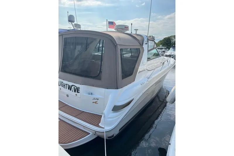 Slide: The Image of 1997 Sea Ray Sundancer 330 docked, featuring a beige canopy and sleek white exterior. - 3