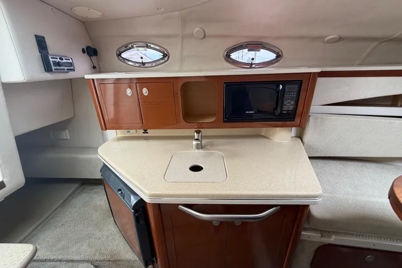Slide: The Image of 2008 Sea Ray 270 Amberjack cabin with kitchenette, featuring sink, microwave, and storage cabinets. - 17