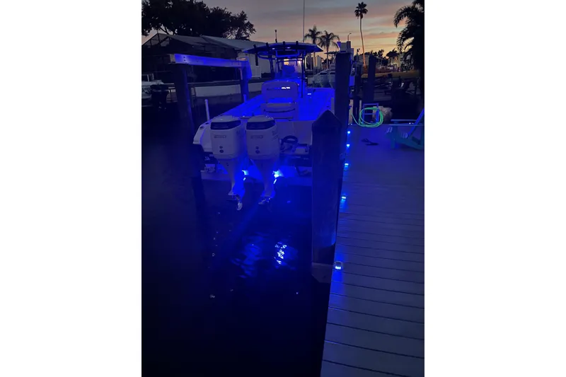 Slide: The Image of 2020 Sea Chaser 27 HFC CC boat with blue LED lights docked at sunset. - 46