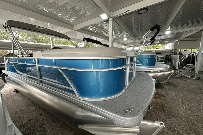 The Image of 2026 Sweetwater EX2086SFLX pontoon boat with blue exterior under a covered area. - 1
