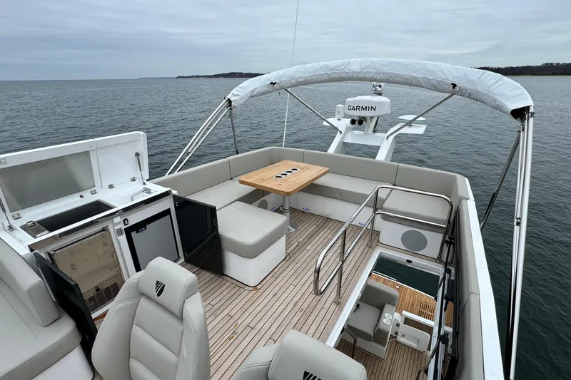 Slide: The Image of 2024 Fairline Squadron 50 yacht flybridge with seating, table, and Garmin equipment on open water. - 63