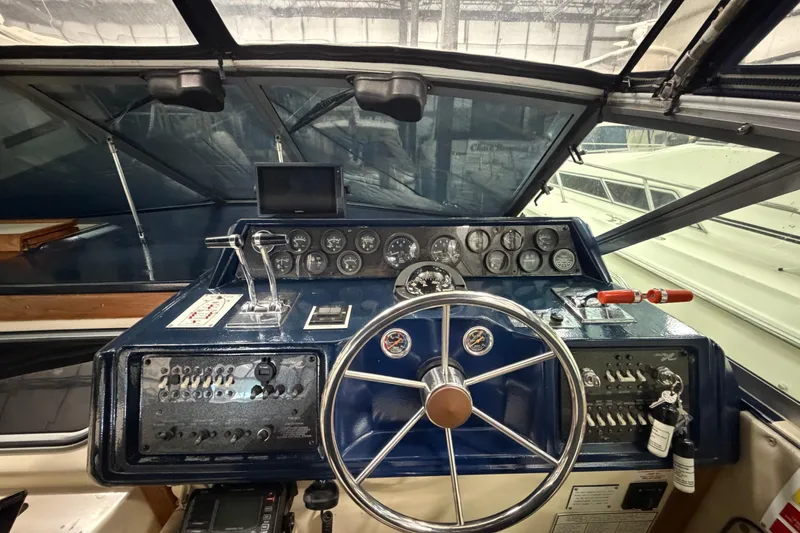 Slide: The Image of 1986 Sea Ray 340 Sundancer helm with gauges, steering wheel, and controls in a marina setting. - 12