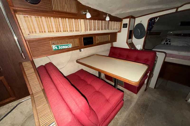 Slide: The Image of 1986 Sea Ray 340 Sundancer cabin interior with red seating and dining table. - 16