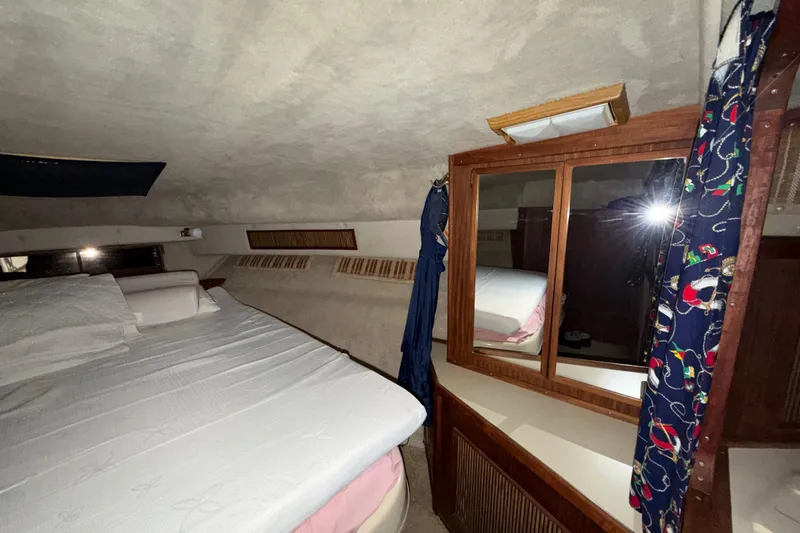 Slide: The Image of 1986 Sea Ray 340 Sundancer cabin interior with bed, mirror, and nautical-themed curtains. - 21