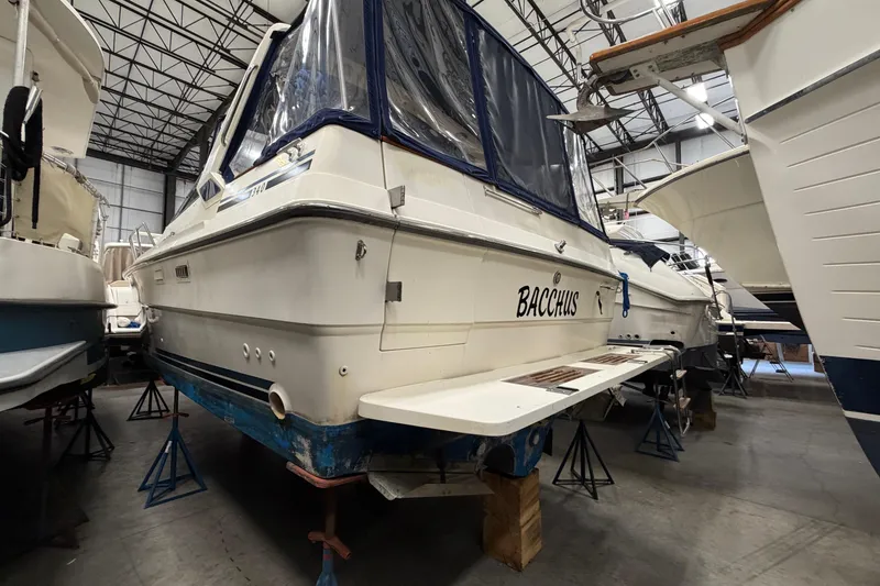 Slide: The Image of 1986 Sea Ray 340 Sundancer boat in storage, named "Bacchus," with blue trim and covered cockpit. - 3