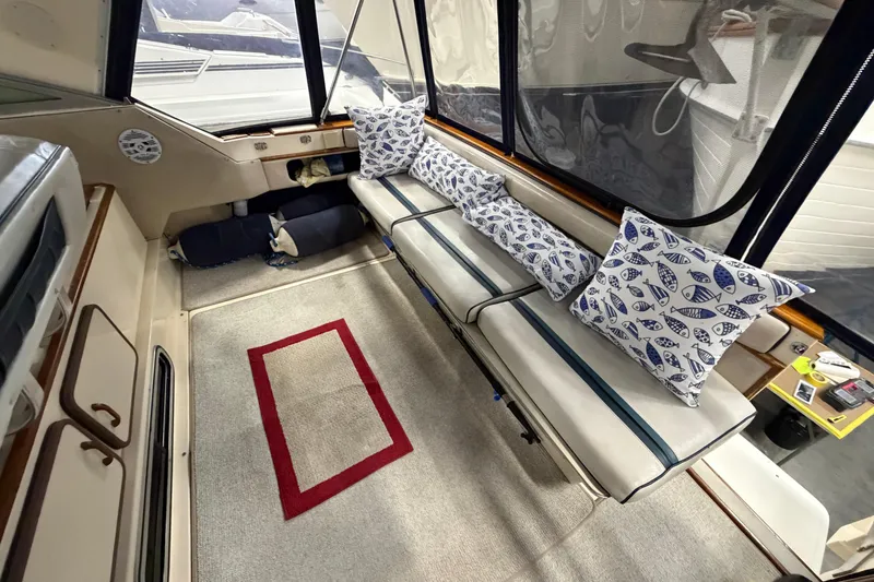 Slide: The Image of Interior of 1986 Sea Ray 340 Sundancer with cushioned seating and nautical-themed pillows. - 9